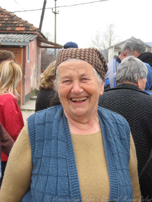 Una signora anziani sorride, in fila per ricevere il pacco famiglia preparato dall'Associazione
